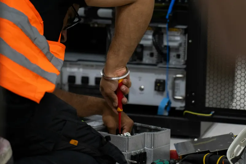 Technician in hi-vis terminating cables into an enclosure, tools laid out on the floor