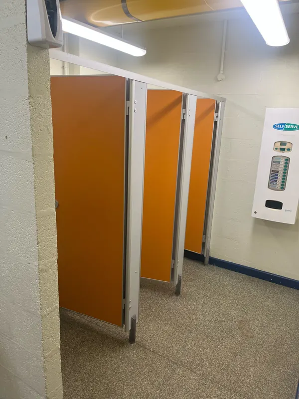 Washroom before: worn orange cubicles